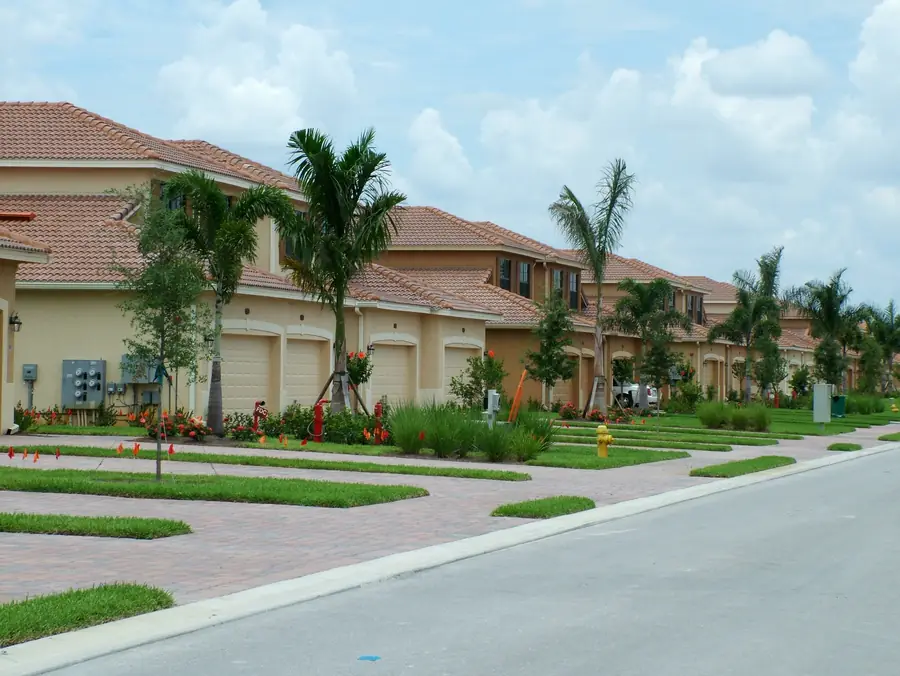 A finished row of two-storey townhomes with tile roofs, palm trees and paver driveways